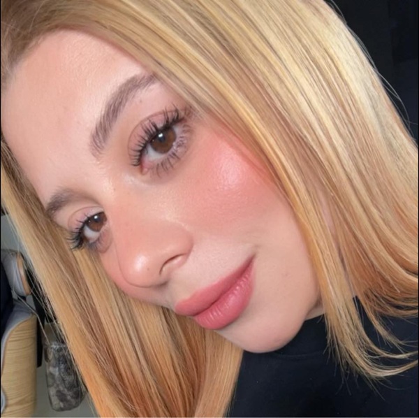 femeie blonda imbracata in negru cu parul drept zambeste si face un selfie