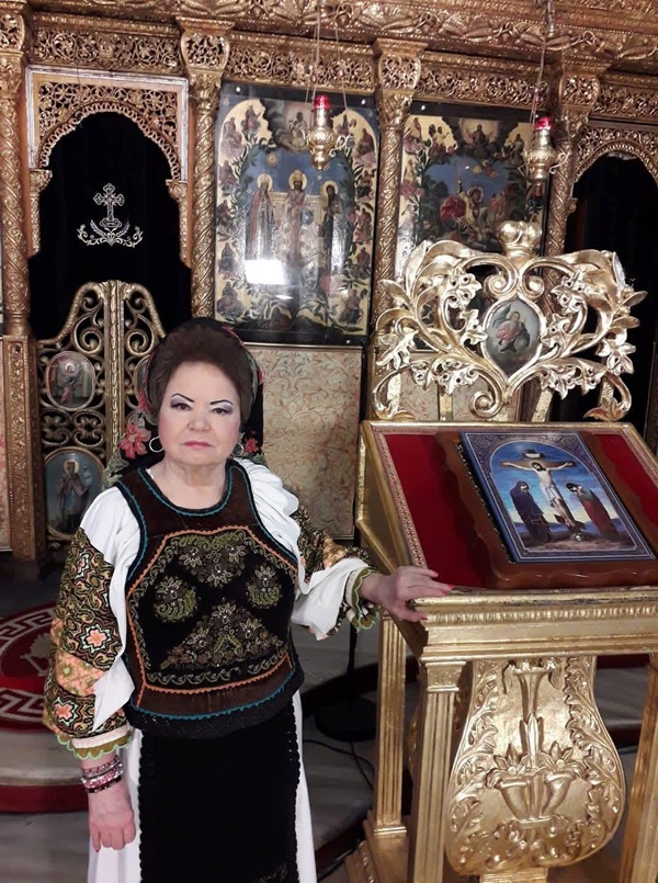 saveta bogdan in costum popular in biserica langa o icoana