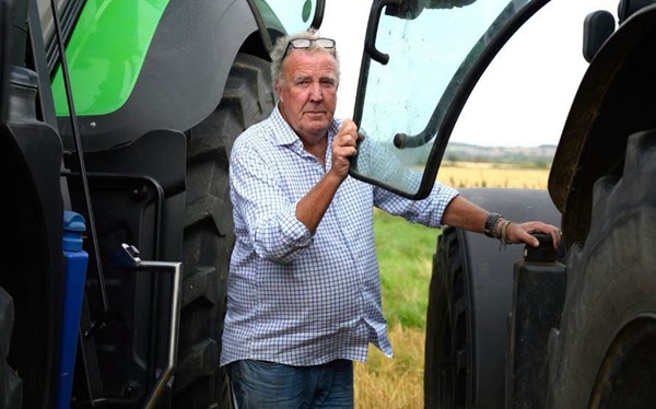 jeremy clarkson in camasa deschisa la culoare sta intre 2 tractoare
