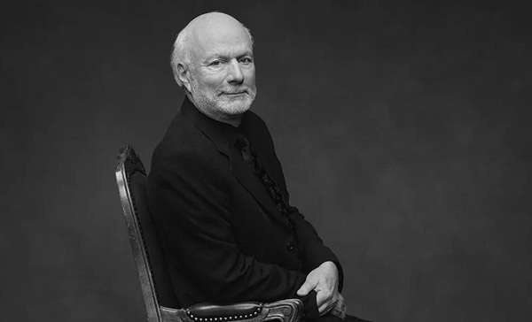 james burrows imbracat in pulover negru sta pe un scaun