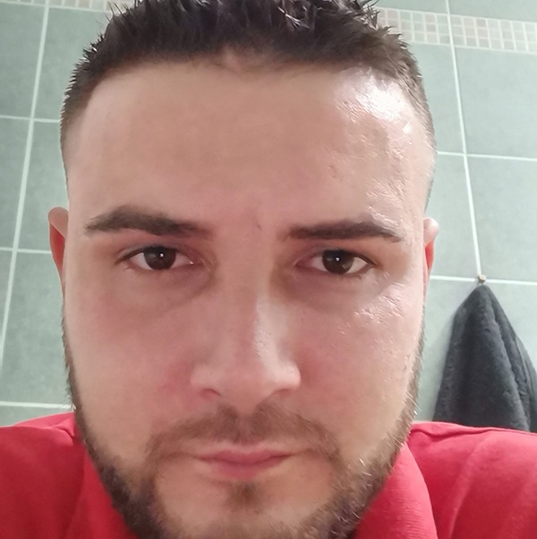 barbat cu barba si mustata imbracat in rosu se uita fix in camera
