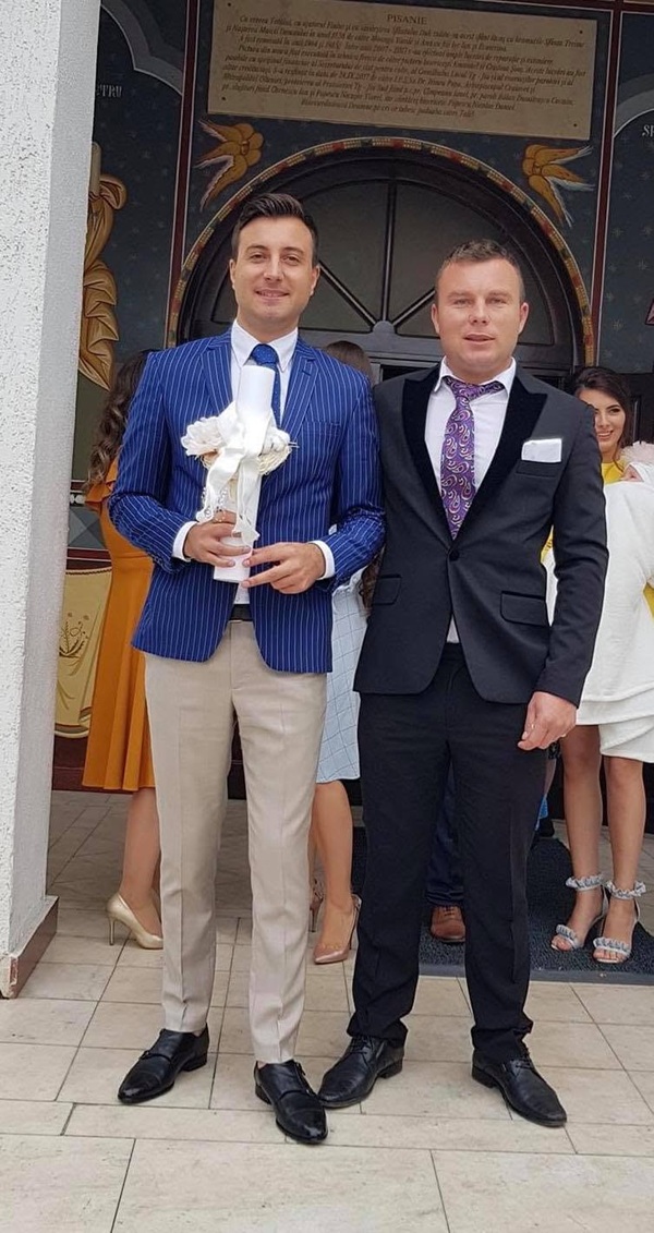 valentin sanfira in costum albastru tine o lumanare de botez alba in mana alaturid e fratele lui la iesire din biserica
