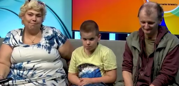 ioana tufaru in rochie alba cu bleu sta pe o canapea impreuna cu sotul si fiul ei la o emisiune
