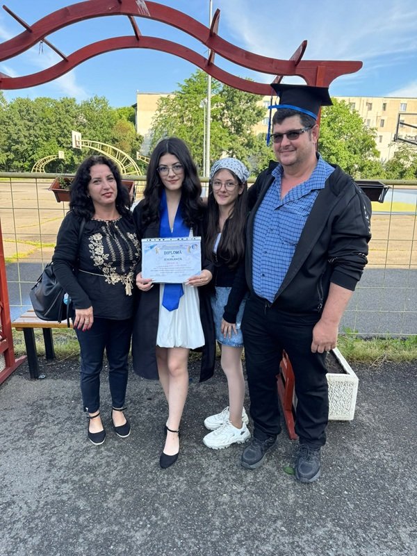 mama tata si doua fete la ceremonia de absolvire a stefaniei bonciu care tine in mana o diploma