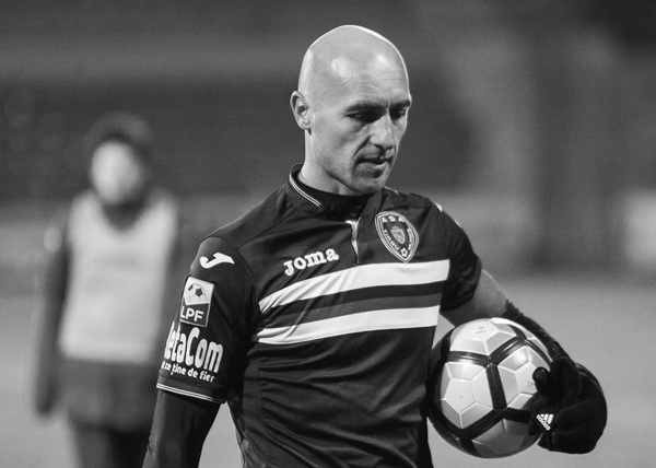 gabi muresan cu o minge la subrat priveste pe terenul de fotbal in jos