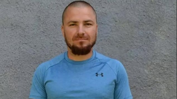 emil ganj imbracat in tricou albastru sta langa un perete