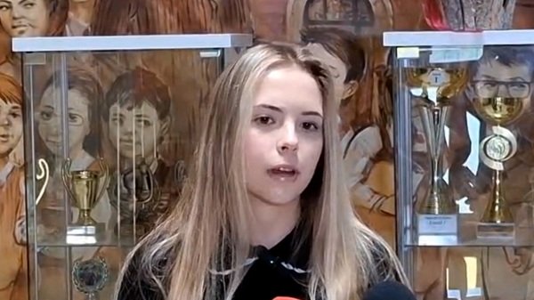fata blonda cu parul desprins da un interviu printre medalii si trofee