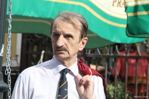 jurnalistul mircea m ionescu in camasa alba cu cravata gri isi tine pe spate cu mana sacoul