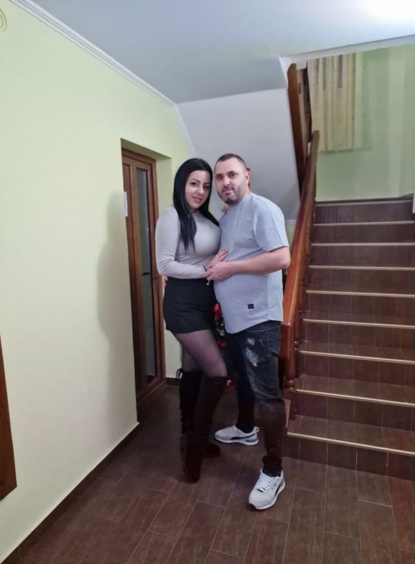femeie imbracata in alb cu fusta neagra impreuna cu un barbat intr-o scara de bloc