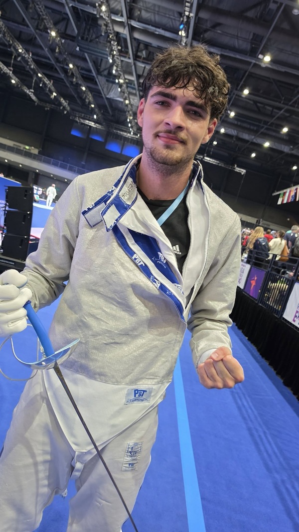 radu nitu in costum alb de scrima cu spada in mana pe plansa albastra