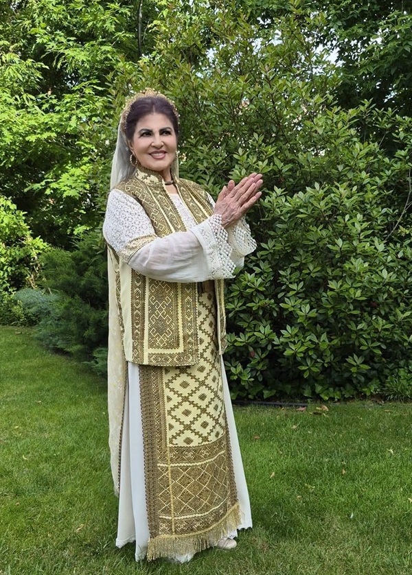 irina loghin in natura inconjurata de verdeata imbracata in costum popular romanesc cu fota de culoare aurie