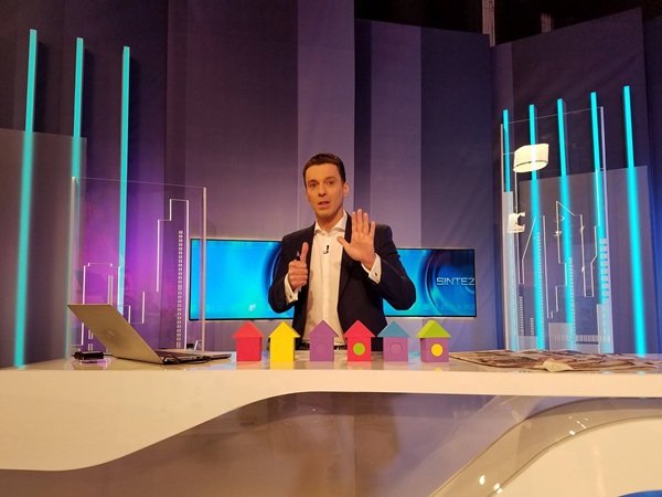 mircea badea in costum negru si camasa alba la pupitrul emisiunii in platoul de filmare