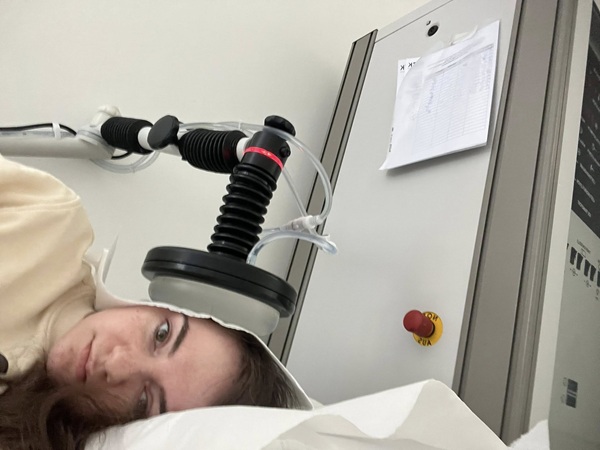 femeie satena pe un pat de spital ii apasa un aparat pe ureche