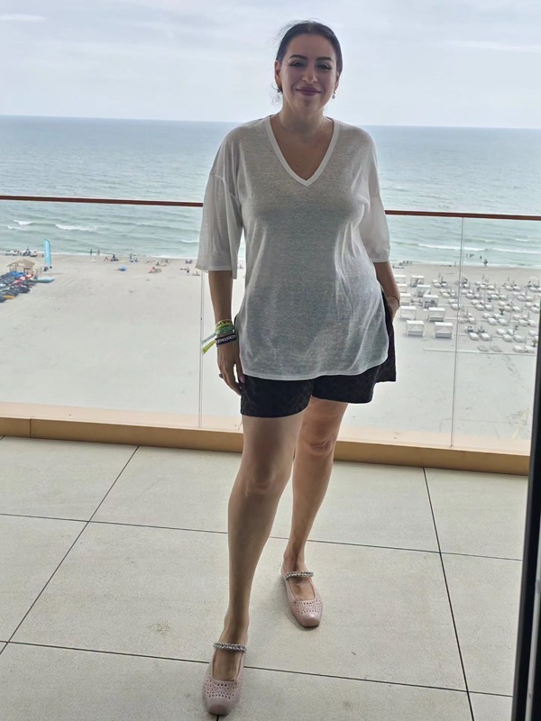 oana roman in tricou alb si pantaloni scurti negri pe balcon la malul marii