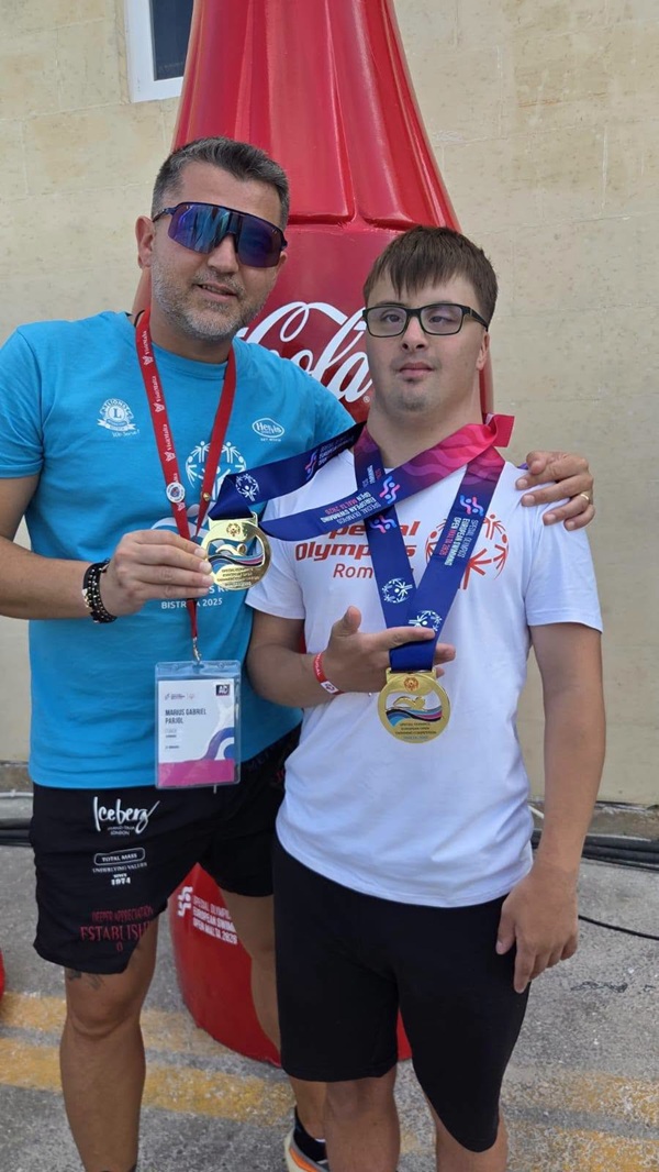 erik in tricou alb cu doua medalii la gat langa antrenorul sau