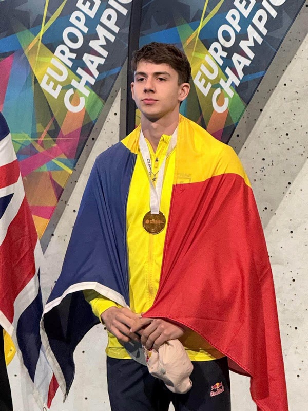 darius rapa in pantaloni negri cu o medalie la gat si tricolorul pe umeri
