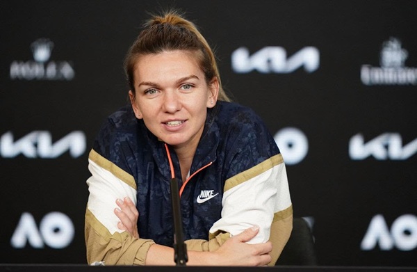 simona halep in tricou alb si vesta neagra in fata unui microfon