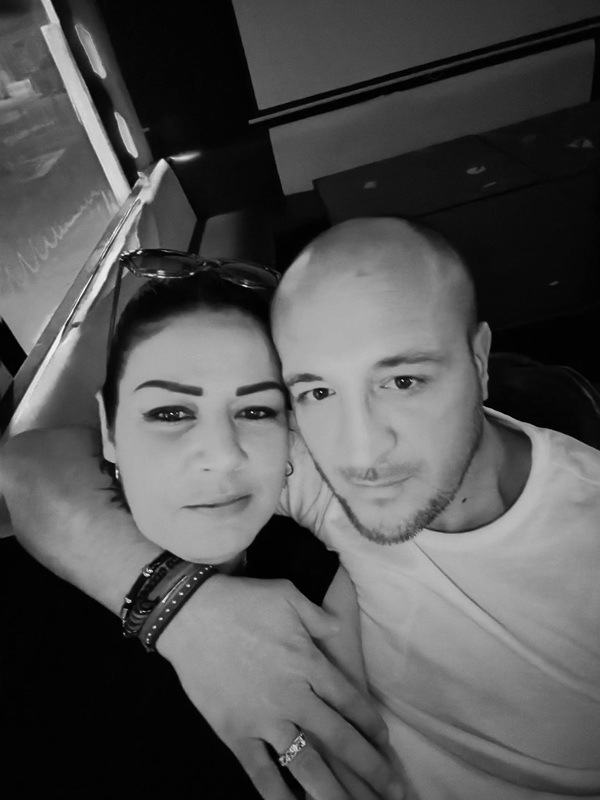 poza alb negru cu o femeie in negru cu parul prins tinuta in brate de barbat imbracat in tricou alb