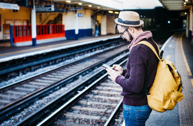 barbat cu telefonul in mana la metrou