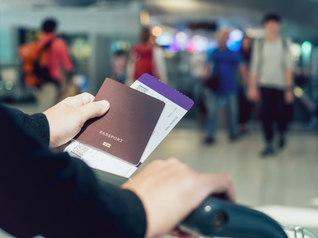 barbat in aeroport cu bilet si pasaport in mana