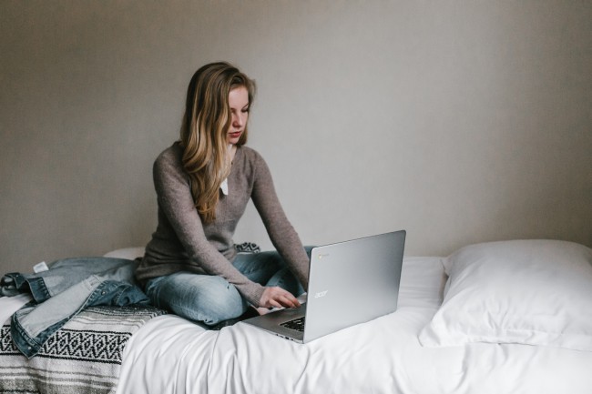 femeie care sta cu laptopul in pat