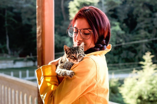 femeie cu ochelari care tine o pisica in brate