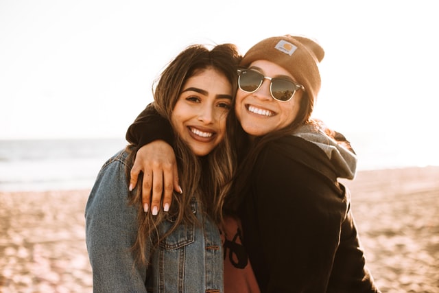 Două fete care râd și se îmbrățișează ca prietene