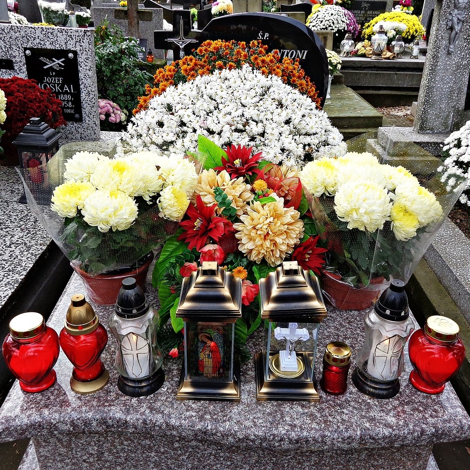 Piatră de mormânt cu multe flori și candele