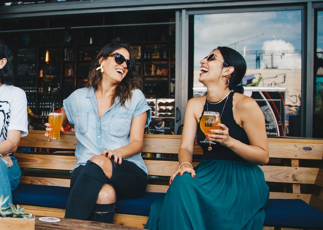 Femei care povestesc și râd cu un pahar de bere în mână
