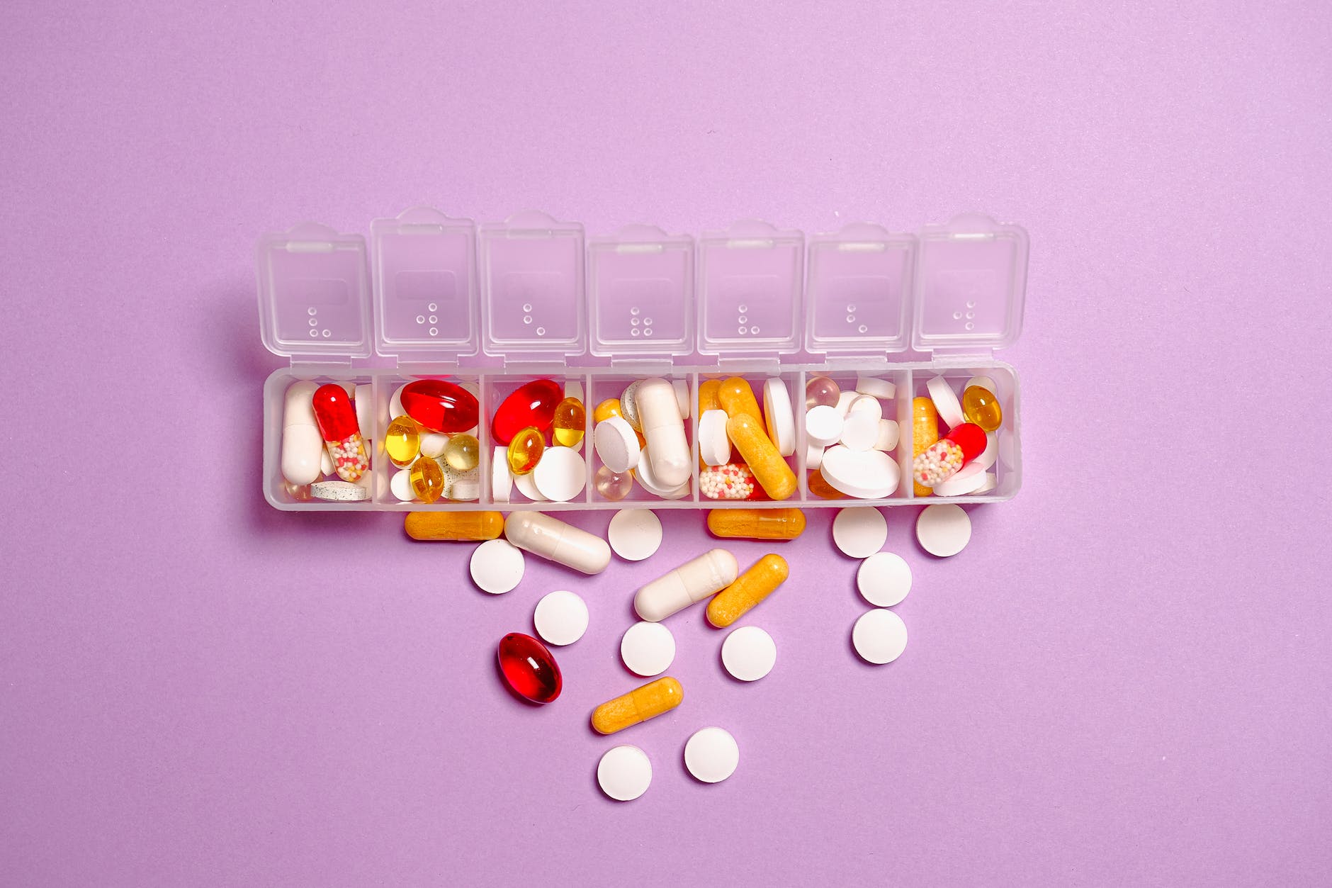 Cutie de mai multe tipuri de medicamente pe un fundal roz