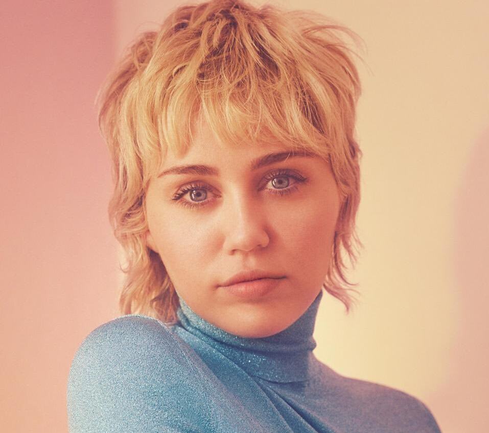 Miley Cyrus Îmbrăcată într-o bluză albastră pe gât