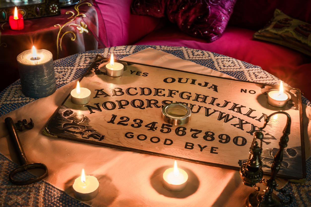 Tabla Ouija pe o masă și lumânări aprinse
