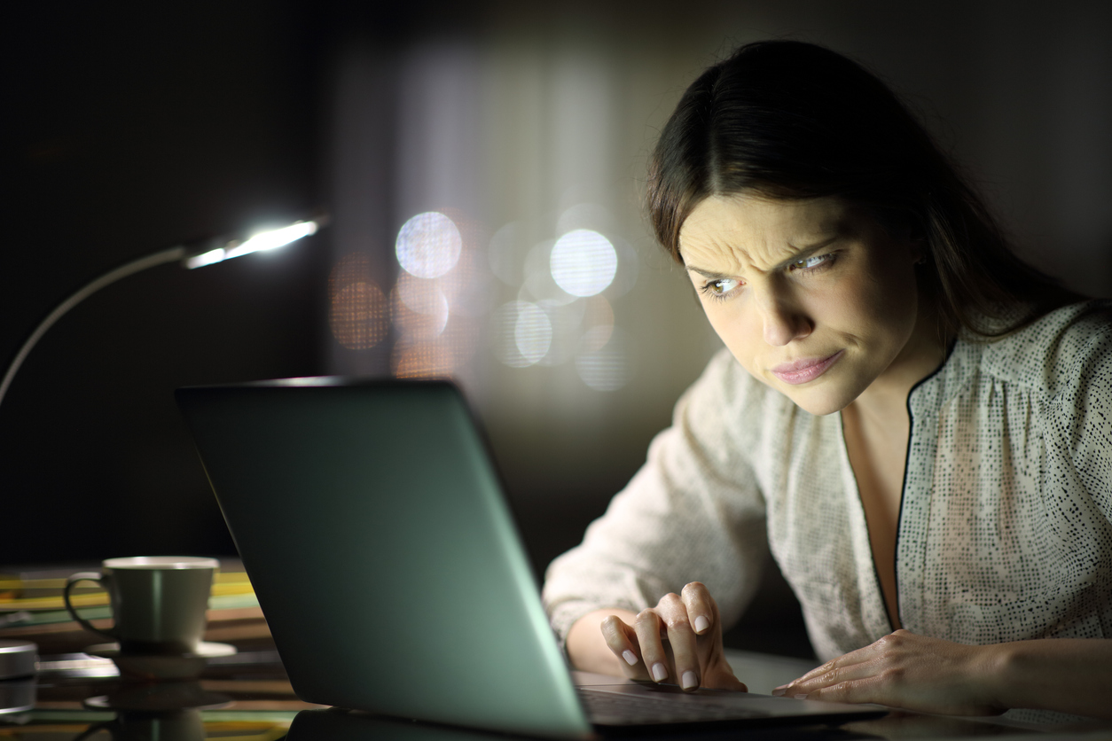Femeie care se uită pe laptop pe întuneric