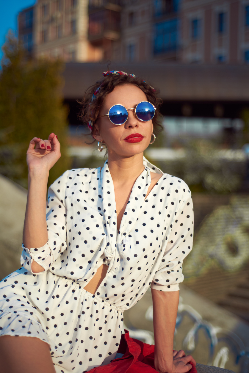 Femeie cu cămășă cu buline și ochelari de soare