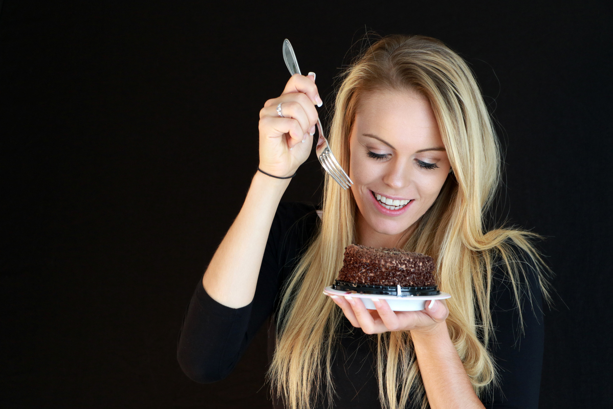 Femeie blondă care mănâncă o prăjitură cu ciocolată