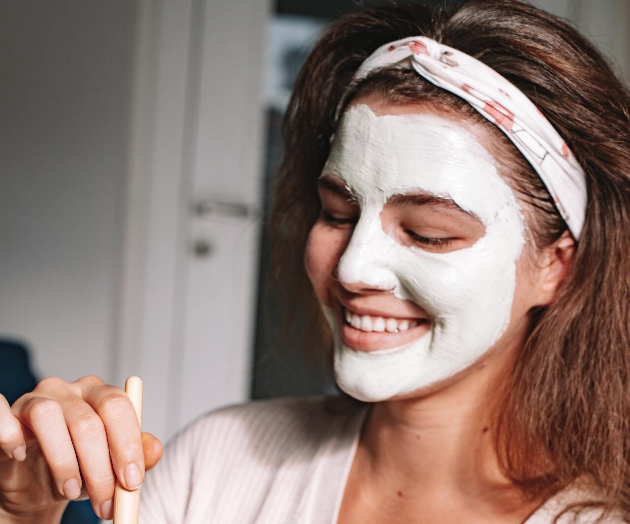 Femeie aplicând mască cosmetică pe față
