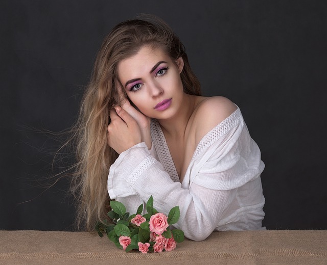 Femeie frumoasă cu o cămașă albă și flori pe masă