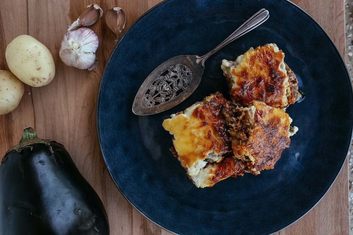 Lasagna pe o farfurie și o vânătă pe masă