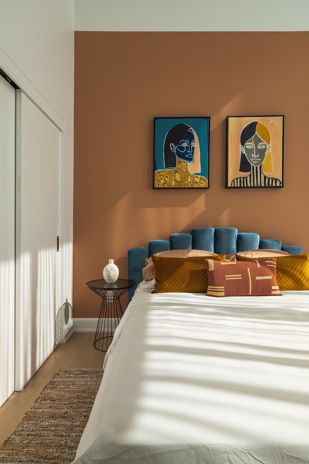 Pat în dormitor pe un perete maro și tablouri colorate