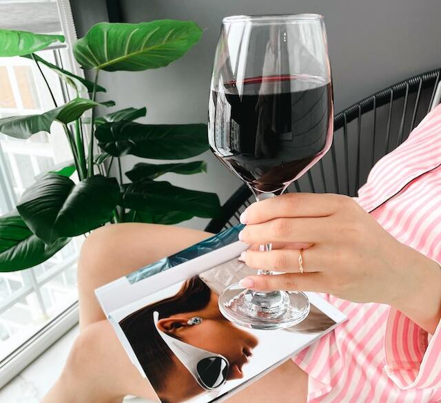 Femeie care ține în mână un pahar de vin roșu