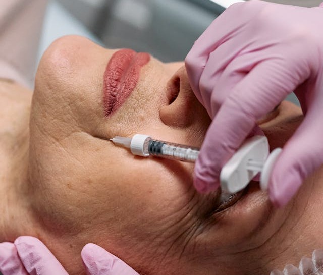 Femeie care-și injectează fillere la ridurile de pe față