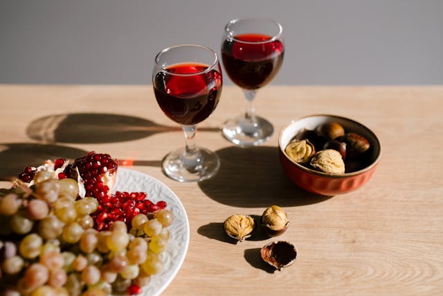 Două pahare de vin roșu, struguri și nuci