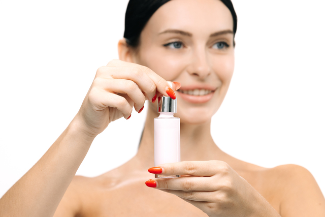Femeie frumoasă cu sticlă de ulei cosmetic