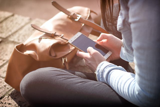 Femeie care sta in sezut si se uita pe telefon