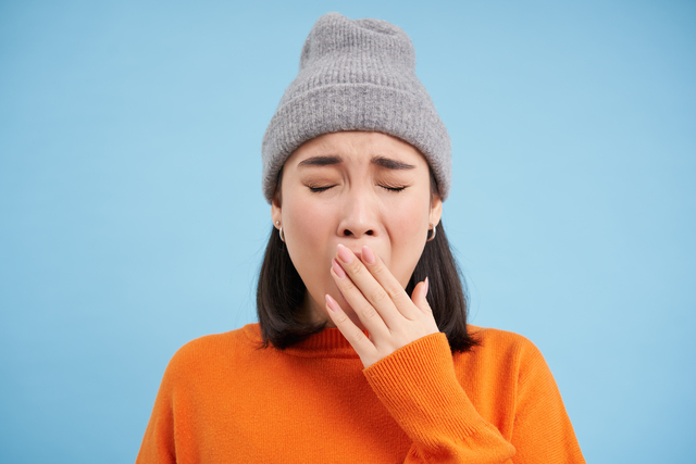 Femeie care casca si puna mana la gura