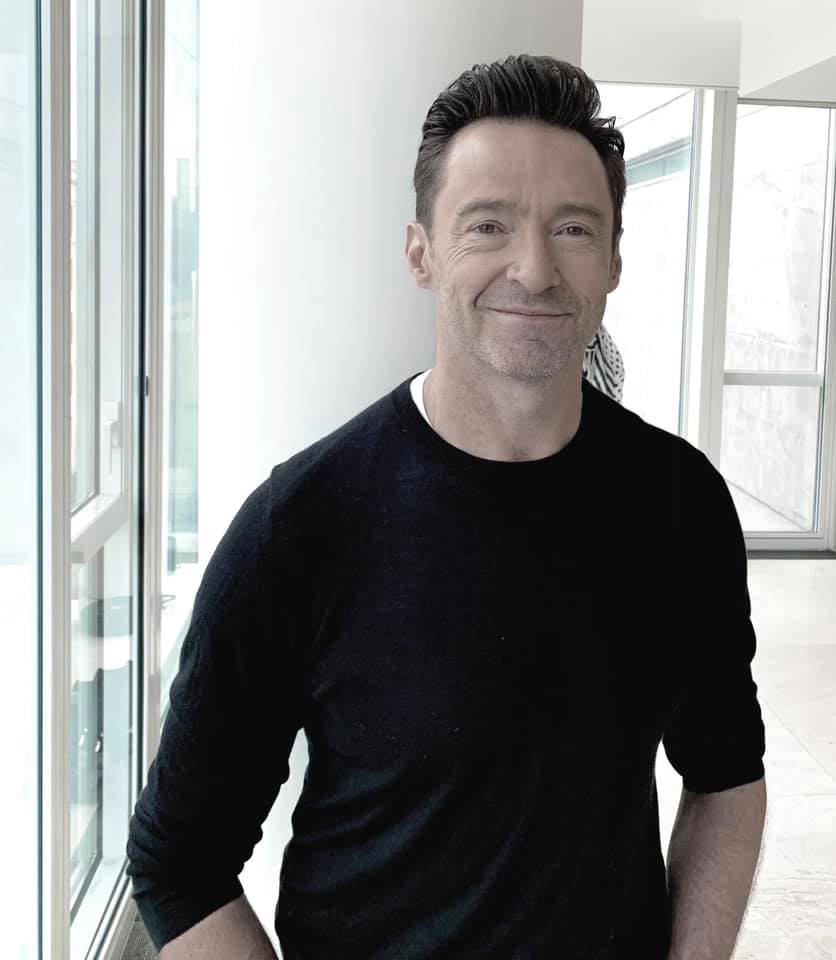 Hugh Jackman, zâmbitor, cu spatele la perete