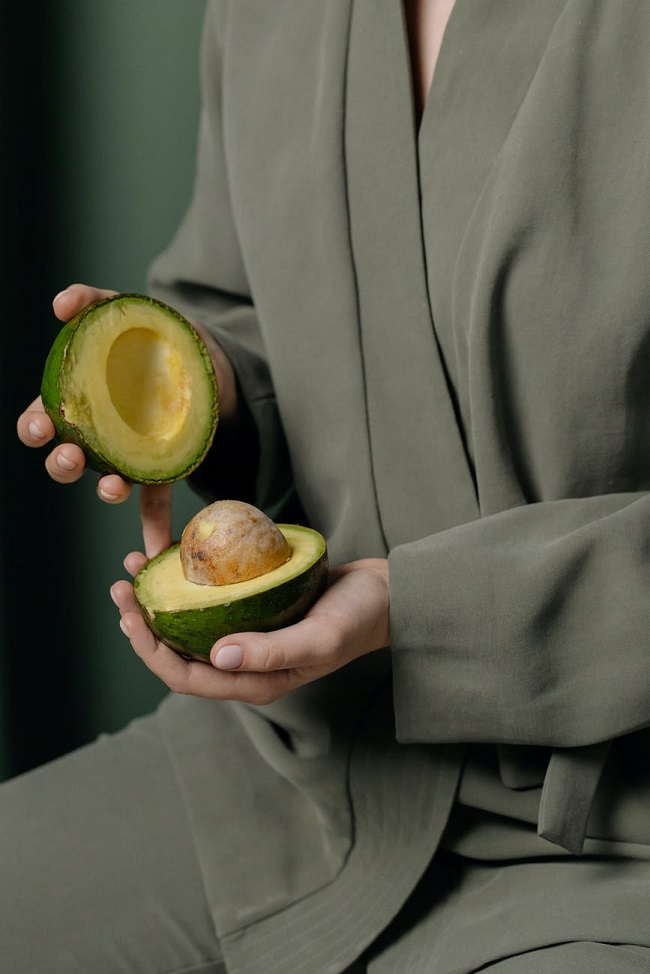Persoană care ține în mână un avocado tăiat pe jumătate