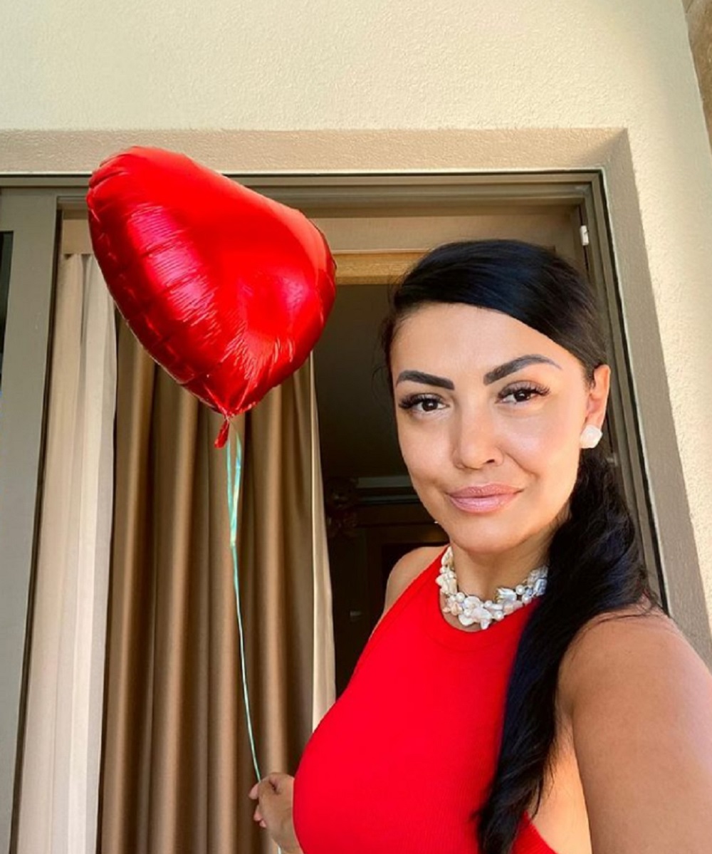 Andreea Mantea într-o rochie roșie, ținând în mână un balon în formă de inimă