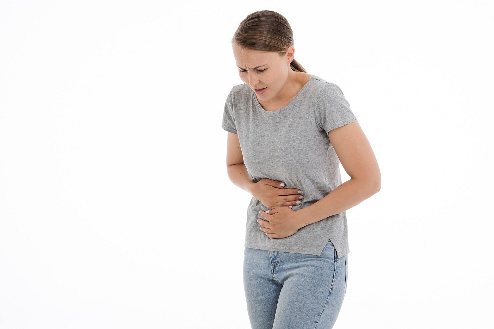Femeie cu durere de pancreas, care își ține mâinile în zona abdominală