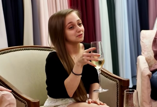 Shauna Rae, cu un pahar de șampanie în mână, într-un episod din serialul „I am Shauna Rae””